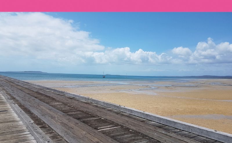 Ein Strand mit Meer im Hintergrund, daneben verläuft eine Straße.